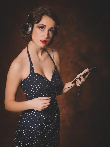 Photo de style vintage de jeune femme écoutant de la musique depuis un smartphone — Photo