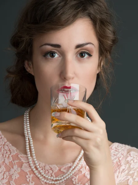 En ung kvinne som holder en drink foran seg – stockfoto