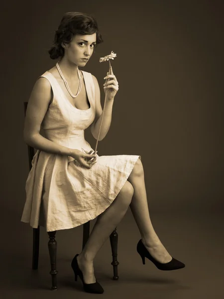 Vintage portrait of young woman sitting with flower — Stock Photo, Image