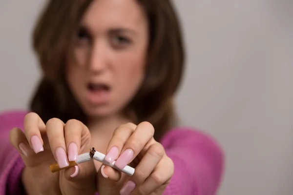 Retrato fuera de foco de una mujer rompiendo un cigarrillo en dos —  Fotos de Stock