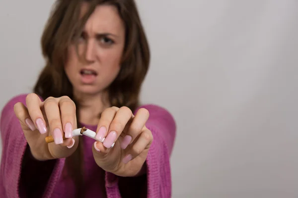 Retrato fuera de foco de una mujer rompiendo un cigarrillo en dos —  Fotos de Stock