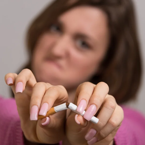 Retrato fuera de foco de una joven rompiendo un cigarrillo en dos —  Fotos de Stock