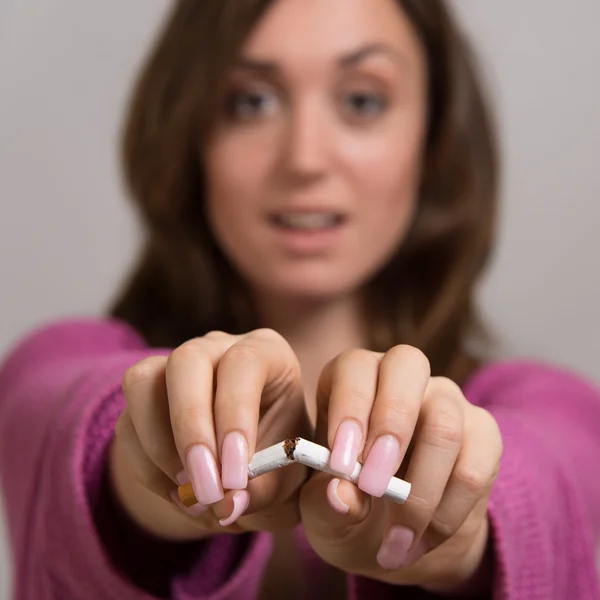 Retrato fuera de foco de una joven rompiendo un cigarrillo en dos —  Fotos de Stock