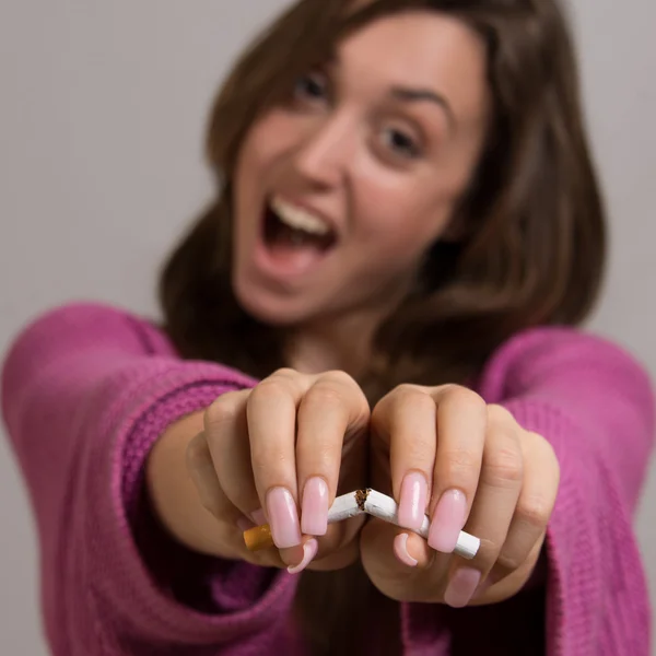 Не в фокусе портрет молодой женщины, разбивающей сигарету пополам — стоковое фото