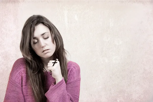 Woman holding a cross intensely, isolated on grey background, READY FOR YOUR TEXT — Stock Photo, Image