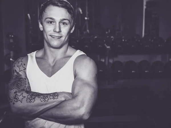 Young bodybuilder standing with arms crossed in a gym — Stock Photo, Image