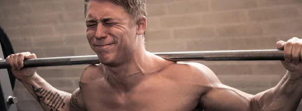 Young man using smith machine in a gym. — Stock Photo, Image