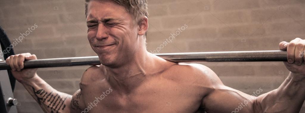 Young man using smith machine in a gym. Stock Photo
