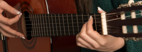 Immagine da primo piano di una donna che suona la chitarra acustica Immagini Stock Royalty Free