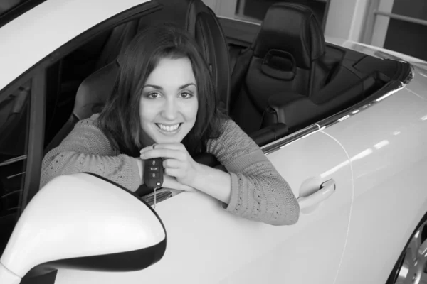 Mujer sosteniendo la llave del coche dentro de concesionario de automóviles — Foto de Stock