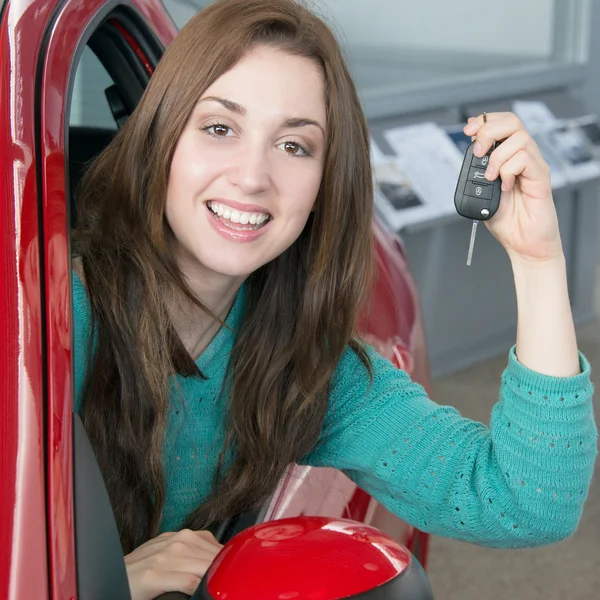 Woman holding car key inside car dealership — Stock Photo, Image