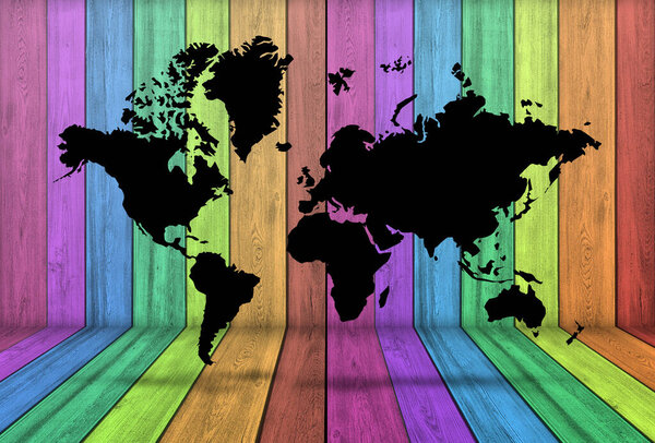 Black World Map in room with wood wall and floor colored with rainbow colors. 