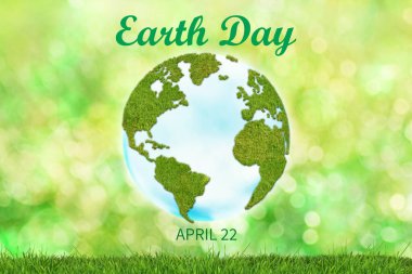 Dünya Günü geçmişi. Çimenden kıtaları olan dünya küresi yeşil üzerinde çözünmüş arka planda otla birlikte..