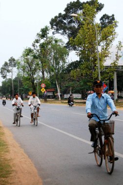 Kamboçyalı insanlar 12 Nisan 2009 'da Siem Reap, Kamboçya' da SiemReap 'in başkentinde trafik Angkor Wat yolunda motosiklet ve bisiklet sürüyorlar.