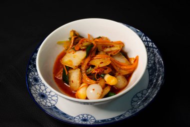 Tayland 'da Bangkok, Tayland' daki restoran kafeteryasında seramik bardakta servis edilen Kore usulü mutfak salatası kimchi veya gimchi yemekleri yapan Taylandlı aşçı.