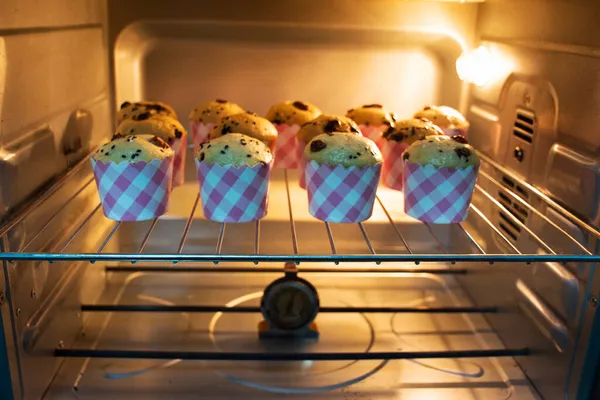 Chef bakery thai people cooking baked cake bananaes cup cake topping chocolate chip bake in electric oven in workshop home for eat and sale at Nonthaburi province of Thailand