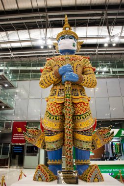 Coronavirus COVID 19 salgını 26 Eylül 2021 'de Suvarnabhumi uluslararası havaalanında Bangkok, Tayland' da patlak verdiğinde maske takan yeni normal ve yaksha koruyucusu ya da dev koruyucu.