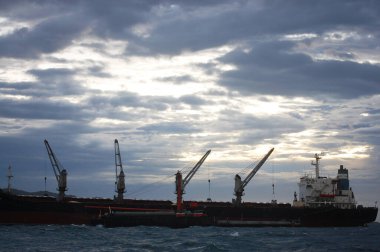 Yük gemisi okyanusta yüzüyor. Tayland 'ın Chonburi kentinde, Sriracha şehrinde, Koh Loy ve Ko Sichang adaları arasında yağış fırtınalı akşam alacakaranlığı saatinde malları transfer etmek için kuyrukta bekliyor.