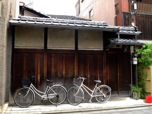 日本の人々は アンティークのレトロな木造住宅の前で自転車のヴィンテージ自転車の停留所に乗る 日本の古いスタイル関西地方の京都市で祇園旧市街地区のHanamikoji通りに — ストック写真