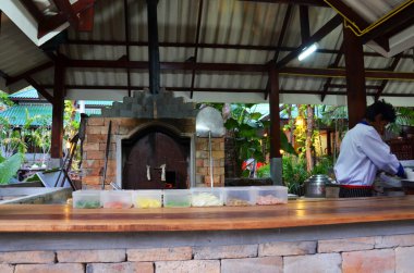 Taylandlı aşçılar eski usul odun sobası kullanır restoranda ekmek pizzası pişirirler gezginlere ikram ederler müşteriler 23 Nisan 2011 'de Tayland' ın başkenti Krabi 'de tatil köyündeki restoranda içki içerler.