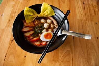 Taylandlı aşçı Tayland usulü erişte, baharatlı ve ekşi Tom domuz rostosu, yumurta soslu sebzeler, çıtır çıtır wonton Tayland 'da Bangkok' taki restoranda seramik kasede servis ediliyor.