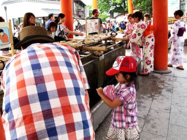 Japonlar geleneksel giysi kimonosu ve yukata el yıkama ayini ya da chozusha ile mitarashi ritüeli ya da 11 Temmuz 2015 'te Japonya' nın Kyoto kentinde Fushimi Inari Tapınağı 'ndaki el taşı havzasında kutsal su giyerler.                               