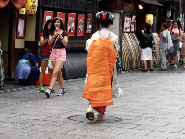 Maiko çırak geyşası ya da geiko, Japon halkı ve yabancı gezginlerle birlikte Gion eski kasabasının Hanamikoji Caddesi 'nde 11 Temmuz 2015' te Japonya 'nın Kansai kentinde yürüyüş yapan sanatçılar.