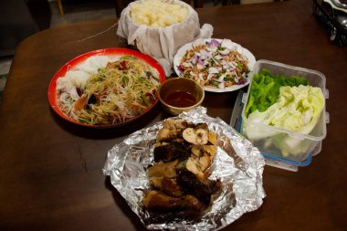 Geleneksel Kuzey Tayland yemeği seti ya da yerel Tayland mutfağı yemek paketi somtam yapışkan pirinç laab ve kai yang aile bireyleri için ahşap masada servis edilir Nonthaburi, Tayland 'daki evde içki içerler.