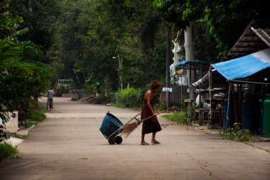 Budist keşiş yaşlı adam günlük temizlik işleri Wat Tham Krabok 'un avlu parkı bahçesinde ya da Tayland' ın Saraburi bölgesindeki Phra Phutthabat bölgesinde Thamkrabok tapınağında.