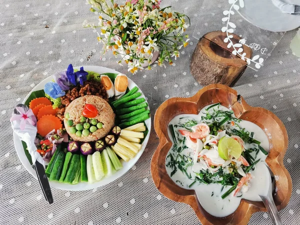 Traditional local thai southern food Stir fried rice with chilli paste dip sweet pork and salted egg variety vegetable served with coconut milk vegetables soup with shrimp on dish plate at restaurant