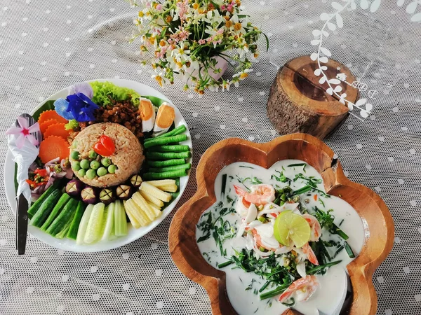 Traditional local thai southern food Stir fried rice with chilli paste dip sweet pork and salted egg variety vegetable served with coconut milk vegetables soup with shrimp on dish plate at restaurant