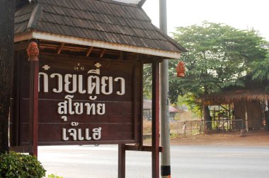 Tahta etiket bilgileri ve Taylandlılar için restoran kafe binası yabancı gezginler Si Satchanalai şehrinde 5 Aralık 2010 'da Sukhothai, Tayland' da bir şeyler içmek için seyahat ederler.