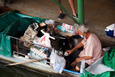 Taylandlı yaşlı kadınlar, 20 Mart 2022 'de Nonthaburi, Tayland' da yerel Wat Takhian Yüzen Pazarı 'ndaki bir tüccar dükkanına nakliye ve taşımacılık yaparak kürek çekiyor.