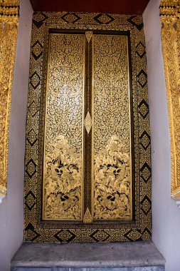 Antik yıkıntı duvar resimleri ve freskler, Tayland 'ın Nonthaburi kentindeki Wat Pho Bang O tapınağını ziyaret eden Tayland' lı insanlar için antik binanın ahşap kapısına resim yapıyorlar.