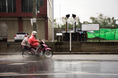 View landscape countryside rural and traffic road with thai people driving riding and biking on street while weather raindrop raining storm at Bangbuathong city in Nonthaburi, Thailand