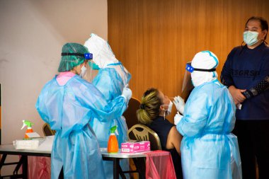 Taylandlı memur, 25 Nisan 2022 'de Bangkok, Tayland' da oteldeki yolcuların hızlı antijen test kitlerini test ederek Coronavirus hastalığı Covid-19 veya Corona virüsü CVid 19 'un sağlıklı olup olmadığını kontrol etti.