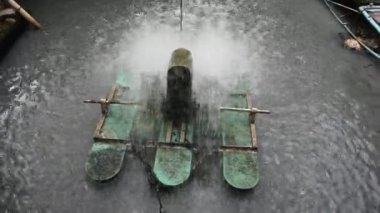 Atık suda oksijen üreten yüzey havalandırma makineleri Tayland 'ın Nonthaburi kentindeki havuz havuzunda arıtma suyu için yel değirmeni sistemini hareket ettiriyor.