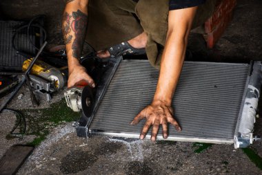 Taylandlı erkek teknisyenler, 18 Haziran 2022 'de Nonthaburi, Tayland' da araba tamirhanesinde çelik kapağı kesen taştan elektrikli aletler kullanıyorlar.