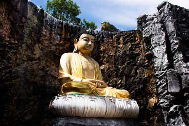 Tayland 'ın Samut Sakhon kentindeki Ban Phaeo şehrindeki Wat Laksi Fare Samosorn tapınağının bahçe şelalelerinde dua eden insanlar için bahçedeki güzel Buda heykeli.