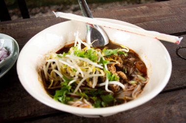 Geleneksel Tayland yemekleri Kanom jeen Nam Ngeo veya Noodles pirinçli vermicelli Kuzey Tayland köri soslu sebze yemeği Chiang Rai, Tayland 'daki yerel bir restoranda seramik tabakta servis ediliyor.