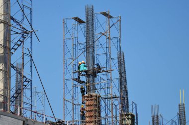 Asian labor people and thai labour workers use machine and heavy machinery working builder new structure tower high-rise building on scaffold at construction site at capital city in Bangkok, Thailand