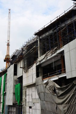 Asian labor people and thai labour workers use machine and heavy machinery working builder new structure tower high-rise building on scaffold at construction site at capital city in Bangkok, Thailand
