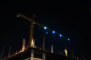 Asyalı işçiler ve Taylandlı işçiler, Bangkok, Tayland 'da gece vakti inşaat alanında inşa edilen yeni yapı kulesi inşaatında makine ve ağır makineler kullanıyorlar.