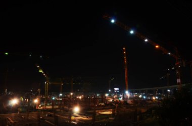 Asyalı işçiler ve Taylandlı işçiler, Bangkok, Tayland 'da gece vakti inşaat alanında inşa edilen yeni yapı kulesi inşaatında makine ve ağır makineler kullanıyorlar.