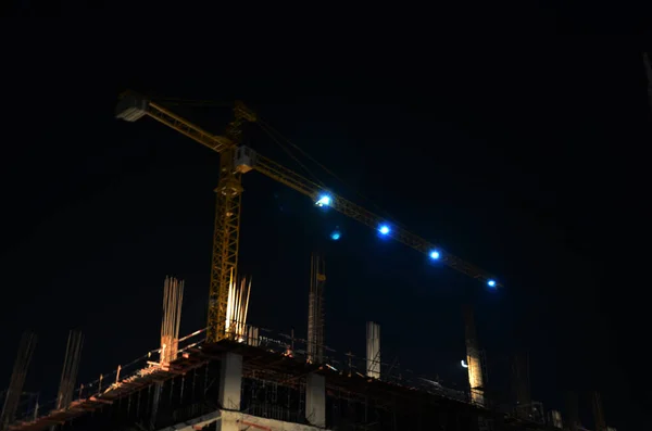 Asian labor people and thai labour workers use machine and heavy machinery working builder new structure tower high-rise building on scaffolding at construction site in night time in Bangkok, Thailand