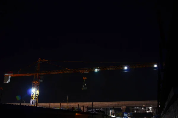 Asian labor people and thai labour workers use machine and heavy machinery working builder new structure tower high-rise building on scaffolding at construction site in night time in Bangkok, Thailand