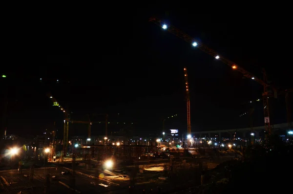 Asian labor people and thai labour workers use machine and heavy machinery working builder new structure tower high-rise building on scaffolding at construction site in night time in Bangkok, Thailand