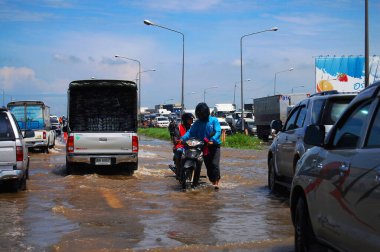 Taylandlılar 20 Ekim 2011 'de Nonthaburi, Tayland' da taşra şehrinde su baskını ya da taşıt trafiği dolu taşıt trafiği yolu ile yolda motosiklet sürüp araba kullanırken