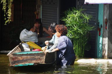 Taylandlı doğal afet kurbanları, 20 Ekim 2011 'de Nonthaburi Tayland' da kırsal kesimde su taşkınları ve kurtarma çalışmalarına yardım ederken, su taşkınları caddesinde suda yüzen araçları kullanıyorlar.