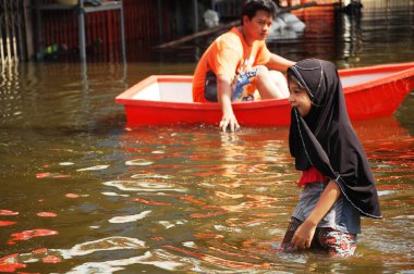 20 Ekim 2011 'de Nonthaburi, Tayland' da kırsal Bang Bua Tanga başkentinde su taşkınları ve sel baskını yolunda yüzerken Taylandlı kız kardeşler ve arkadaşları sokakta yüzüyorlar.
